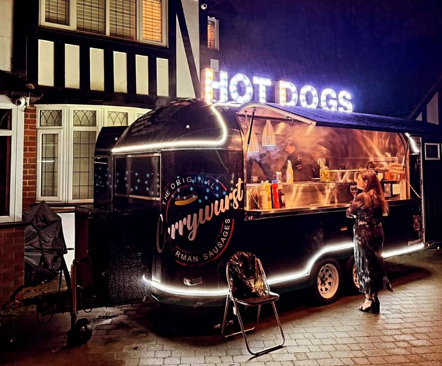 The Currywurst trailer lit up for a private function on a driveway