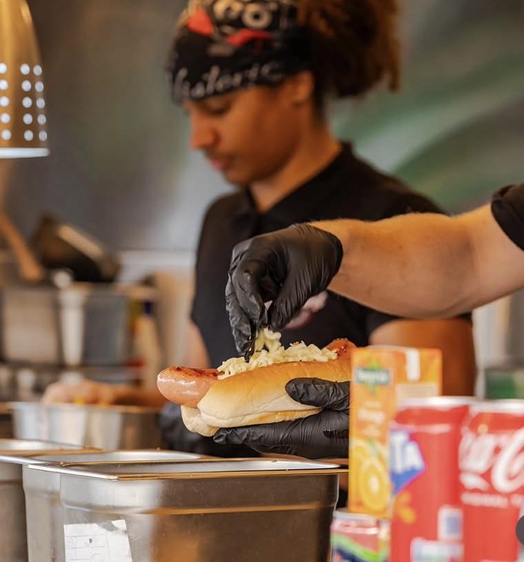 A Currywurst team member preparing a cheese dog